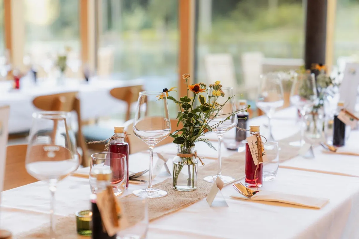 Detail einer festlich gedeckten Hochzeitstafel mit Blumen und Gastgeschenken